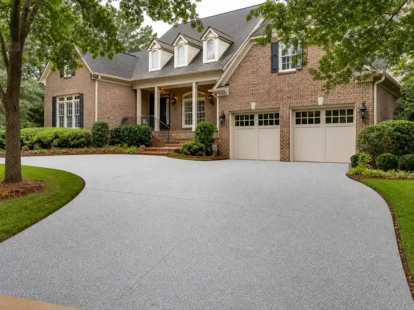 Coated residential driveway in front of a brick home